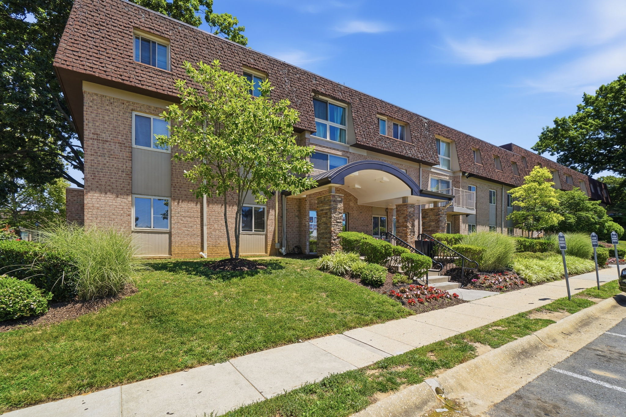 A large brick building with a landscaped front yard.